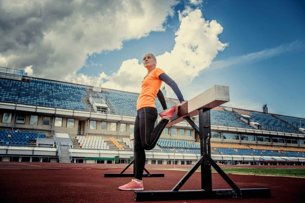 slim-blond-female-sportswear-doing-exercises-stadium-blue-sky-with-white-clouds (1)